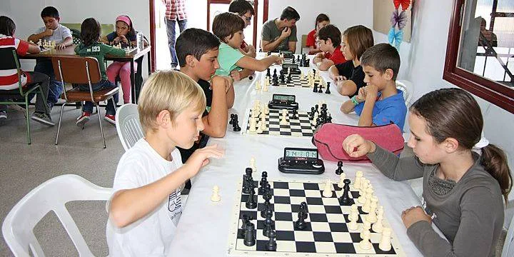 Niños compitiendo en un torneo interno de ajedrez con relojes de competencia en la academia de Los Olivos