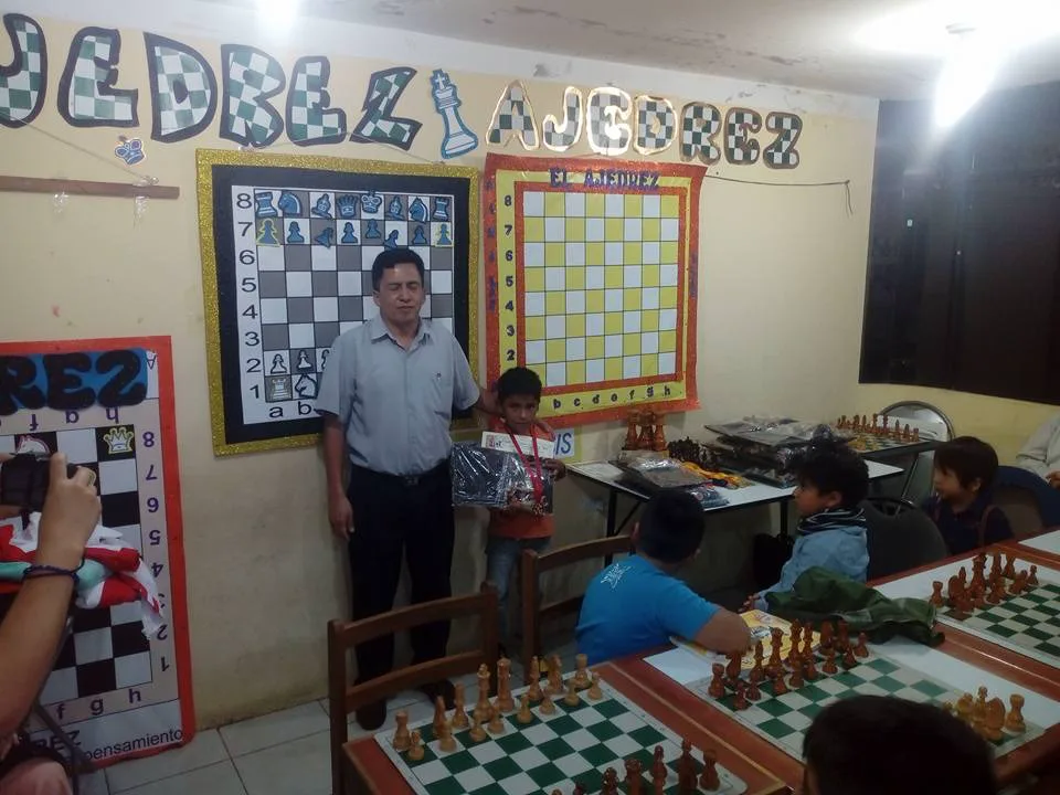 Premiación de un alumno en el aula de la academia de ajedrez de Los Olivos, con tableros murales didácticos